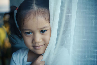 Close-up of cute girl holding curtain