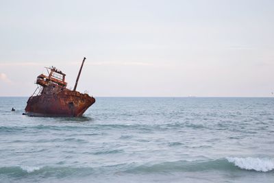 Abandoned boat in sea against sky