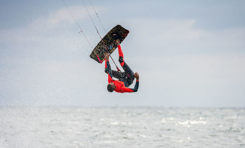 Low angle view of man kiteboarding in sea against sky