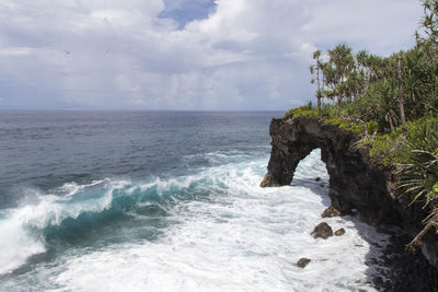 Volcanic coastal cliffs with blue waves breaking during sunny day