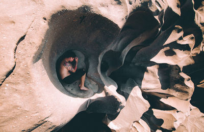 Directly above shot of shirtless man lying down on rock