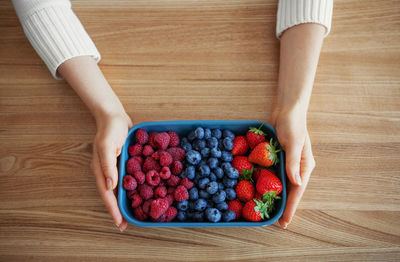 Fresh berries in woman hands. summer berries, strawberries, blueberries and raspberries in bowl 
