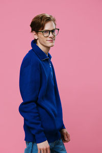 Young man standing against pink background