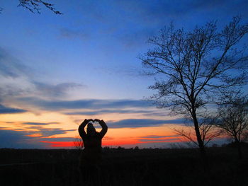 Silhouette man on field against sky during sunset