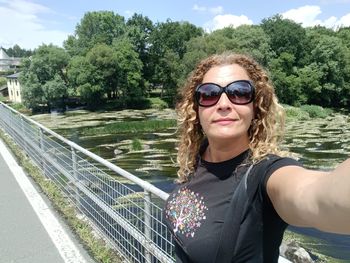 Portrait of young woman standing against bridge