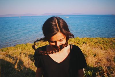 Beautiful young woman looking at sea against sky