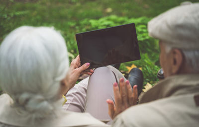 Rear view of couple video calling on digital tablet at park