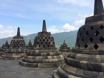 Stupas of temple against cloudy sky