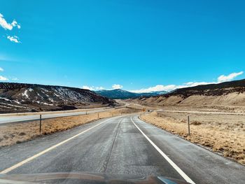 Road leading towards mountains against sky