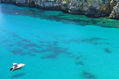 High angle view of boat moored on sea by rocky mountains