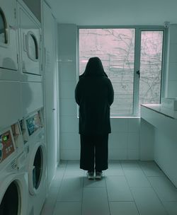 Rear view of woman standing by window