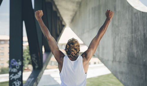 Back view of young man raising his arms