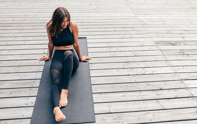 High angle view of woman looking away while sitting on exercise mat