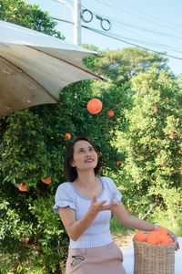 Young woman standing by tree against plants