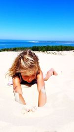 Full length of girl lying on sand at beach against sky