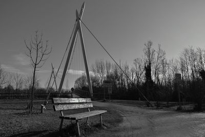 Empty park bench on field against sky