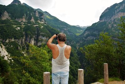 Rear view of man photographing mountains