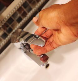 Cropped hand holding knob of faucet