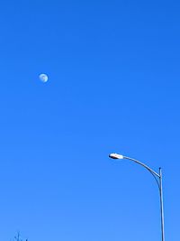 Low angle view of street light against blue sky and moon