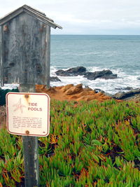 Information sign on beach against sky