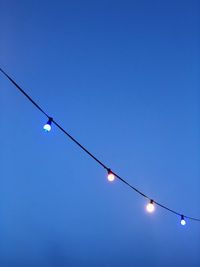 Low angle view of lighting equipment against clear blue sky