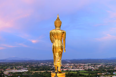 Golden walking buddha statue at wat phrathat khao noi temple during twilight, nan province, thailand