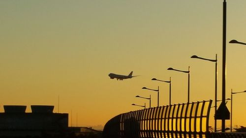 Airplane flying against clear yellow sky