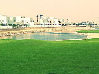 Scenic view of golf course against sky in city