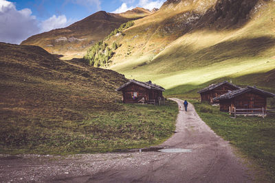 Road amidst houses and mountains against sky