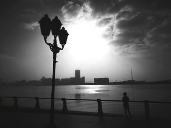 Silhouette of city at riverbank during sunset