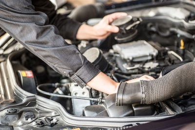 Midsection of mechanic repairing car engine