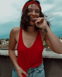 Portrait of smiling woman standing against sky