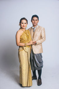 Portrait of young couple standing against white background