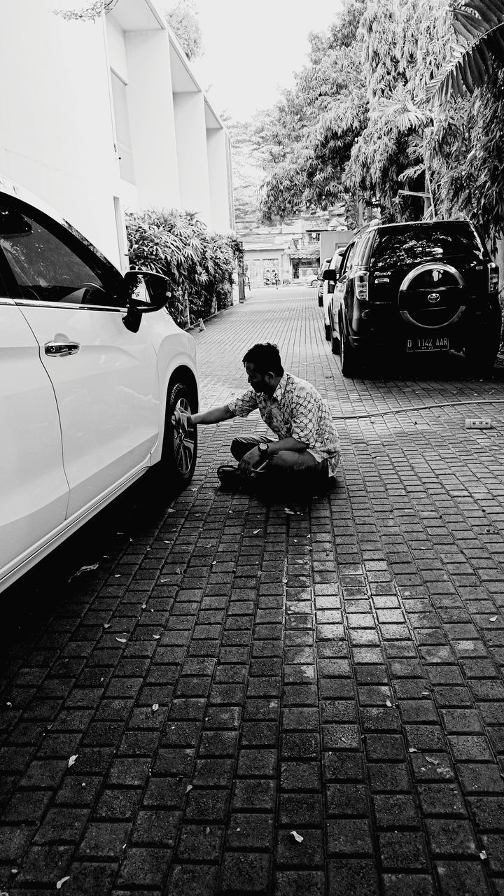 MAN SITTING IN FOOTPATH