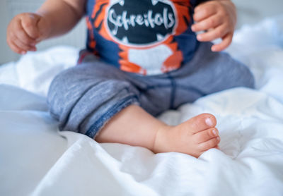 Midsection of baby girl sitting on bed