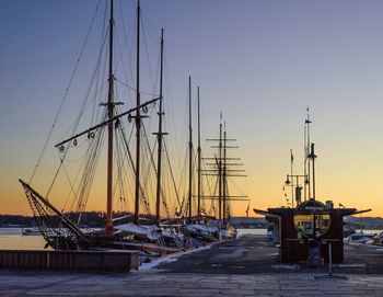 Sailboats moored at harbor against clear sky