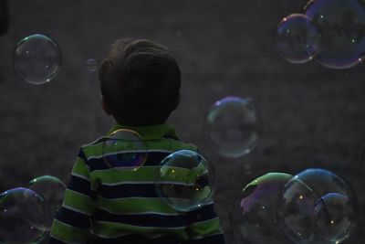 Rear view of boy standing amidst bubbles