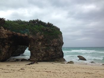Rock formation on beach against sky