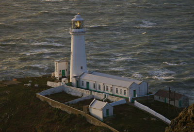 High angle view of lighthouse amidst sea and buildings