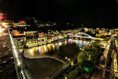 High angle view of illuminated bridge over river in city at night