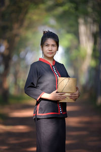 Portrait of smiling woman standing with wicker container on street