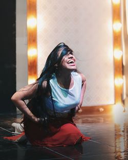 Smiling woman dancing on illuminated stage