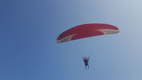 Low angle view of person paragliding against clear blue sky