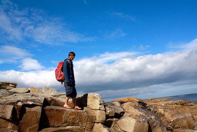 Man standing on rock against sky