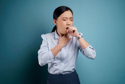 Young woman standing against blue background
