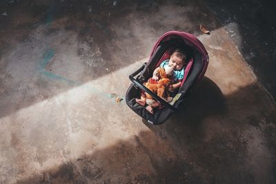 High angle view of toddler with toy in baby carriage outdoors