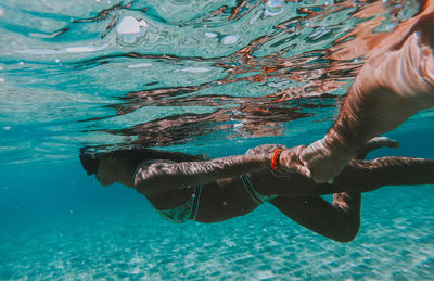 Woman holding hand of man while swimming in sea