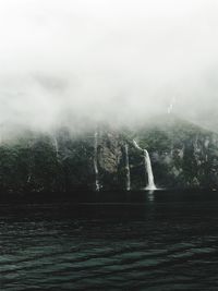 Scenic view of waterfall in forest during foggy weather