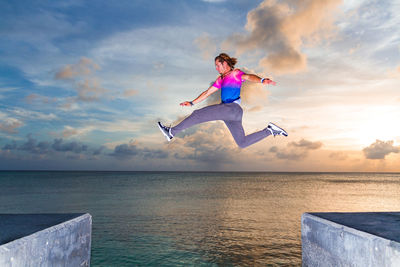 Woman jumping in sea against sky