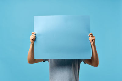 Low section of person holding umbrella against blue background